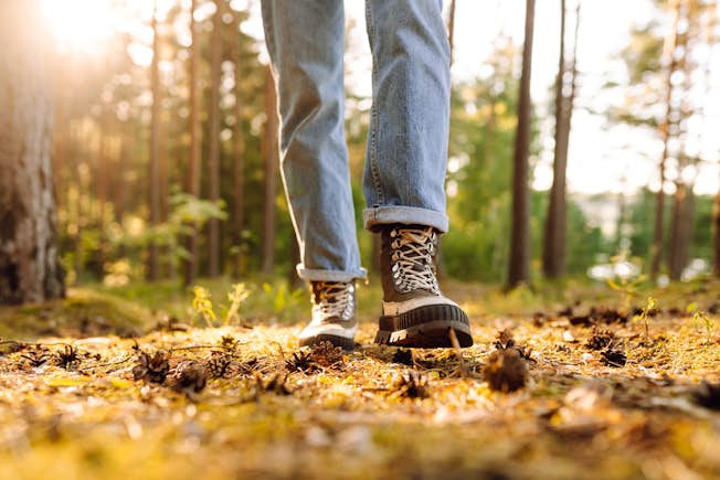 A person walking in a wooded area wearing hiking boots.